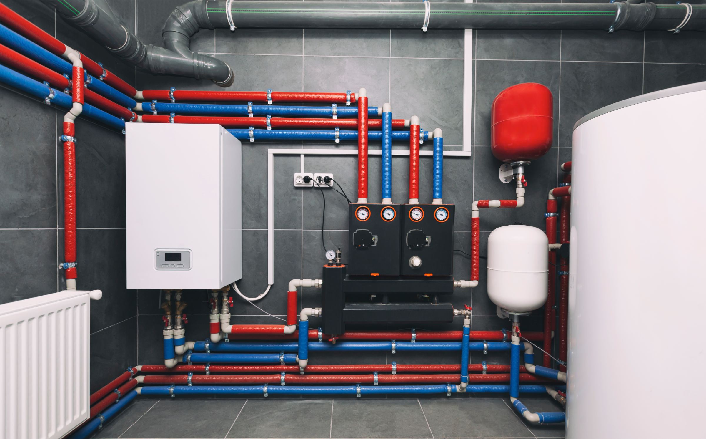 Residential mechanical room with water heater, manifold gauges and insulated supply lines